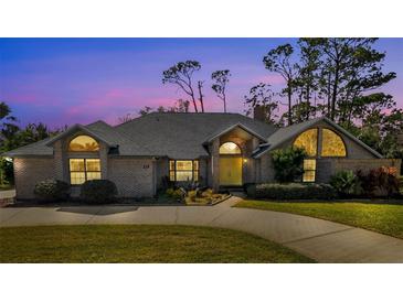 Brick house with gray roof, yellow door, and landscaped yard at 217 Pleasant Valley Dr, Daytona Beach, FL 32114