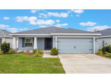 Single-story home with gray exterior, attached garage, and landscaped lawn at 220 Foxtail Loop, Davenport, FL 33837