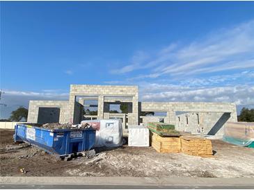 New construction of a modern home showcasing concrete block walls and prepped lumber under a bright blue, partially cloudy sky at 2710 Ravencliffe Ter, Oviedo, FL 32765