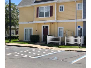 Exterior view of a yellow two-story building with white picket fence at 4560 Yellowgold E Rd # 108, Kissimmee, FL 34746