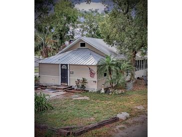 Tan house with metal roof, American flag, and landscaping at 590 W Vine St, Bartow, FL 33830