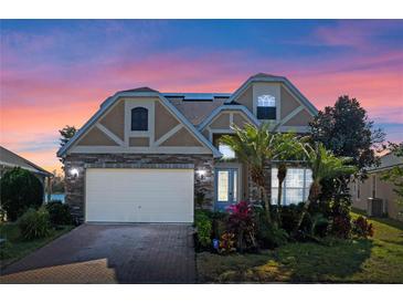 Two-story house with stone accents and a three-car garage,solar panels,landscaped yard at 820 Spring Oak Cir, Orlando, FL 32828