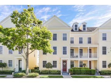 Tan three-story townhome with white columns, red door, and landscaping at 1407 Chatfield Pl, Orlando, FL 32814