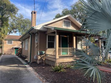 Charming bungalow with a teal door, brick driveway, and well-manicured landscaping at 415 N Shine Ave, Orlando, FL 32803