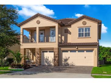 Two-story house with tan exterior, two-car garage, and balcony at 10233 Henbury St, Orlando, FL 32832