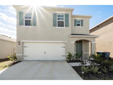 Two-story house with a white garage door and green shutters at 2630 Angel Falls Dr, Davenport, FL 33837