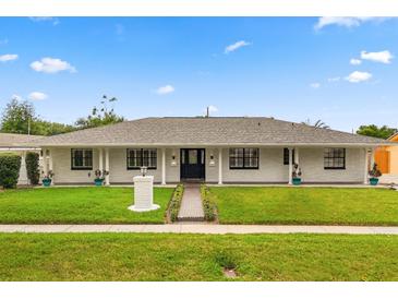 Charming single-story home featuring a well-manicured lawn, brick walkway, and classic architectural details under a bright blue sky at 3010 Bay Tree Dr, Orlando, FL 32806