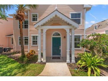 Inviting two-story home with a covered porch, a teal door and a lush, tropical landscape at 3013 Bonfire Beach Dr # 101, Kissimmee, FL 34746