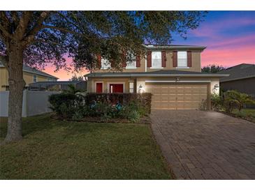Two-story house with red accents, a brick driveway, and landscaping at 3720 Ryegrass St, Clermont, FL 34714