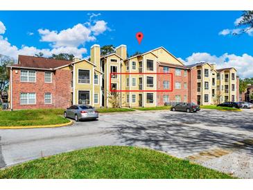 Apartment building exterior featuring brick and yellow siding, balconies, and ample parking at 5600 Devonbriar Way # 204, Orlando, FL 32822