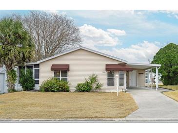 Inviting single-story home features a covered carport, landscaped yard, and awnings for windows at 1207 Palmetto Dr, Lady Lake, FL 32159