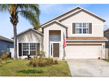 Two-story house with tan exterior, brown shutters, and a two-car garage at 290 Clydesdale Cir, Sanford, FL 32773