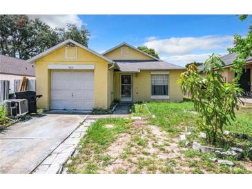 Cute yellow house with a one-car garage and small front yard at 5633 Piney Ridge Dr, Orlando, FL 32808