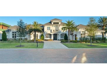 Stunning two-story home boasts a balcony, lush landscaping, and a grand brick driveway at 7017 Via Carmel Way, Orlando, FL 32819