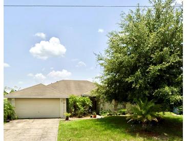 Single-story house with attached garage and large tree in front yard at 1717 Minnow Ct, Poinciana, FL 34759