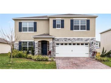 Charming two-story home features stone accents, blue shutters, attached garage, and well-maintained landscaping at 33425 Country House Dr, Sorrento, FL 32776