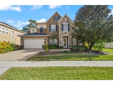 Charming two-story home with stone and brick accents, a well-manicured lawn, and an attached two-car garage at 4943 Cains Wren Trl, Sanford, FL 32771