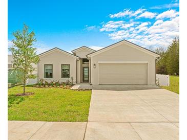 Tan house with two-car garage, landscaping, and a driveway at 6113 Chorus Dr, Mascotte, FL 34753