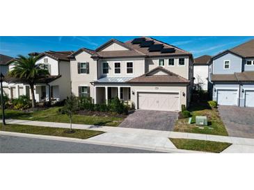 Two-story house with beige siding, solar panels, and a brick driveway at 7613 Wandering Way, Orlando, FL 32836