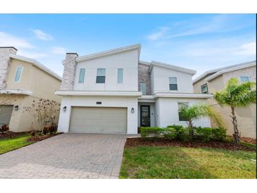 Two-story modern home with gray and white exterior, two-car garage, and landscaped lawn at 8828 Cruden Bay Ct, Davenport, FL 33896