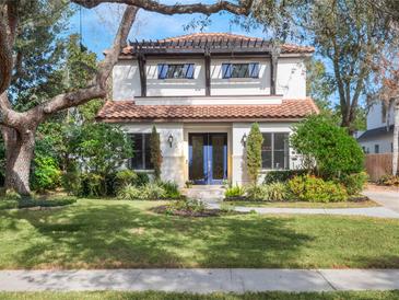 Charming two-story home featuring a tile roof, a pergola over the garage, and a lush landscaped yard at 141 Oakwood Way, Winter Park, FL 32789