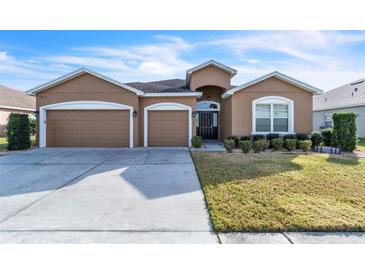 Two-car garage, light brown exterior, and well-manicured lawn at 245 Viola Dr, Auburndale, FL 33823