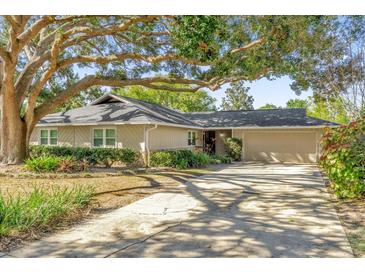 Ranch style home with mature landscaping and a large tree providing shade at 3820 Orange Lake Dr, Orlando, FL 32817