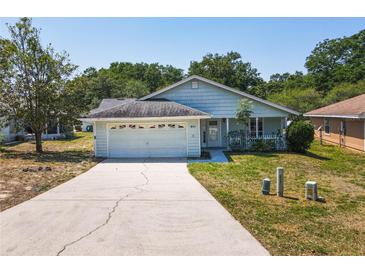 Charming single-story home with light blue siding, attached garage and inviting front yard at 511 Coventry Ct, Mount Dora, FL 32757