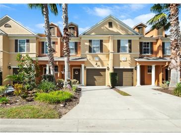 Tan three-story townhome with two-car garage and lush landscaping at 890 Assembly Ct, Reunion, FL 34747