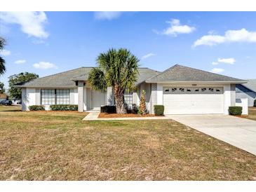 One-story home with a two-car garage and a palm tree in the front yard at 1000 Karen Ridge Ct, Kissimmee, FL 34747