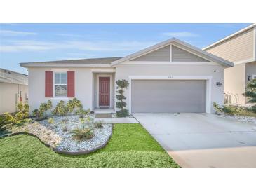 One-story house with red shutters, a two-car garage, and well-manicured landscaping at 283 Archer Way, Haines City, FL 33844