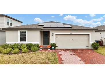 One-story home with solar panels, brick driveway, and landscaping at 3037 Cassidy Ln, Haines City, FL 33844