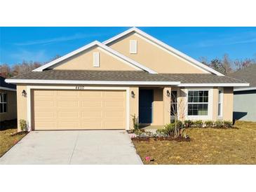 Tan two-story house with a two-car garage and landscaped yard at 4450 Sagefield Dr, Harmony, FL 34773