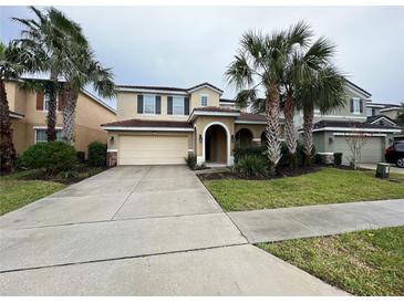 Two-story house with tan exterior, arched entryway, and palm trees at 5298 Wildwood Way, Davenport, FL 33837