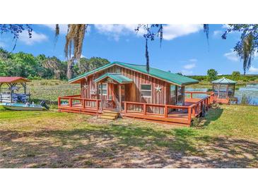 Charming waterfront cottage with a wooden deck, dock, and boat on a picturesque lake at 15040 Ne 248Th Avenue Rd, Fort Mc Coy, FL 32134