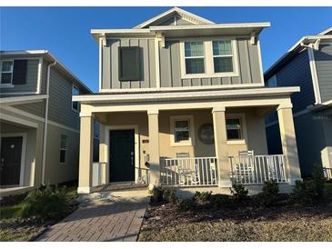 Two-story house with gray siding, front porch, and walkway at 1563 Cross Prairie Pkwy, Kissimmee, FL 34744