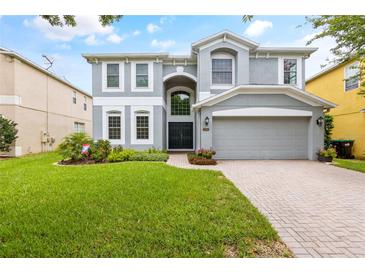 Two-story house with gray siding, a three-car garage, and a well-manicured lawn at 12666 Moss Park Ridge Dr, Orlando, FL 32832