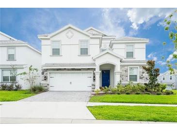 Two-story house with white exterior, stone accents, and a two-car garage at 1584 Sandbagger Dr, Davenport, FL 33896