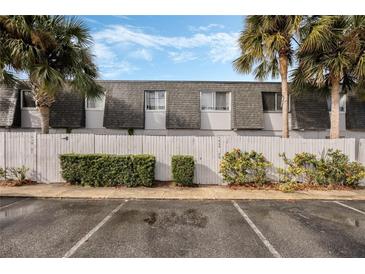 Charming condo building with lush tropical landscaping, including palm trees and manicured bushes and white fence at 1928 Conway Rd # 40, Orlando, FL 32812