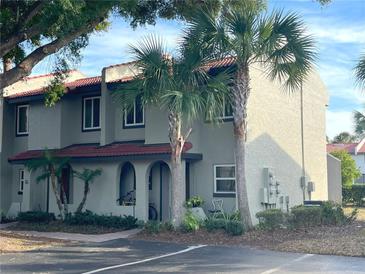 Well-maintained stucco townhouse with tile roof, palm trees, and a small front yard at 3197 Sea World Ct, Kissimmee, FL 34746