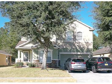 Two-story house with a green facade, stone accents, and a two-car garage at 3260 Sorrel Ct, Deltona, FL 32725