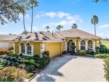 Beautiful yellow house with a brick driveway and lush landscaping at 4 Arika At Lionspaw, Daytona Beach, FL 32124