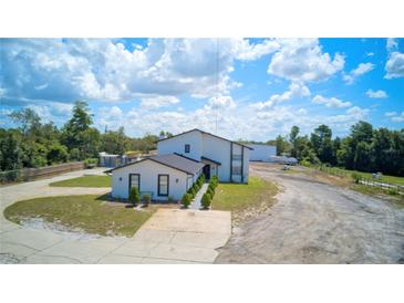 Aerial view of a two-story home with a large yard and driveway at 711 Cypress Ave, Orange City, FL 32763