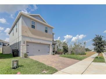Two-story house with gray siding, stone accents, and a two-car garage at 828 Scrub Oak Hammock Rd, Davenport, FL 33837