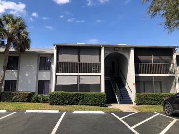 Condo building with stairs leading to upper units, complemented by green shrubbery and a palm tree on a sunny day at 1313 S Pine Ridge Cir # C1, Sanford, FL 32773