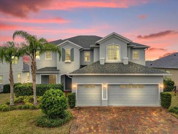 Elegant two-story home boasts a three-car garage, lush landscaping, and a brick driveway at 16737 Meadows St, Clermont, FL 34714