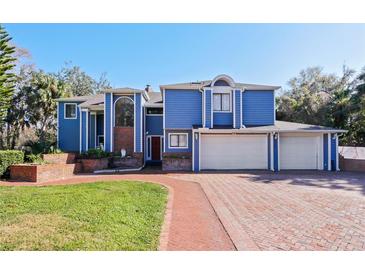 Two-story home with blue siding, brick driveway, and two-car garage at 2395 Windward Cv, Kissimmee, FL 34746