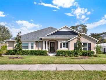 Tan house with gray roof, landscaping, and black shutters at 2583 Grassmoor Loop, Apopka, FL 32712