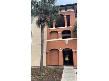 A stucco condo building with multiple levels and a landscaped entrance featuring palm trees at 5548 Metrowest Blvd # 101, Orlando, FL 32811