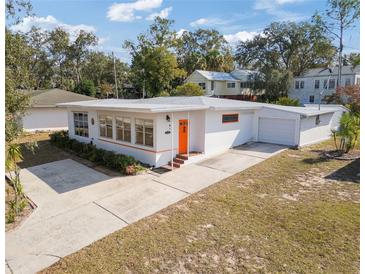 Charming home featuring bright orange accents, a well-maintained lawn, and an attached one-car garage at 814 S Lakeshore Blvd, Lake Wales, FL 33853